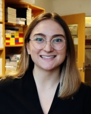 A picture of Celine. She is a young white woman wearing clear-framed 
											glasses. She is smiling.